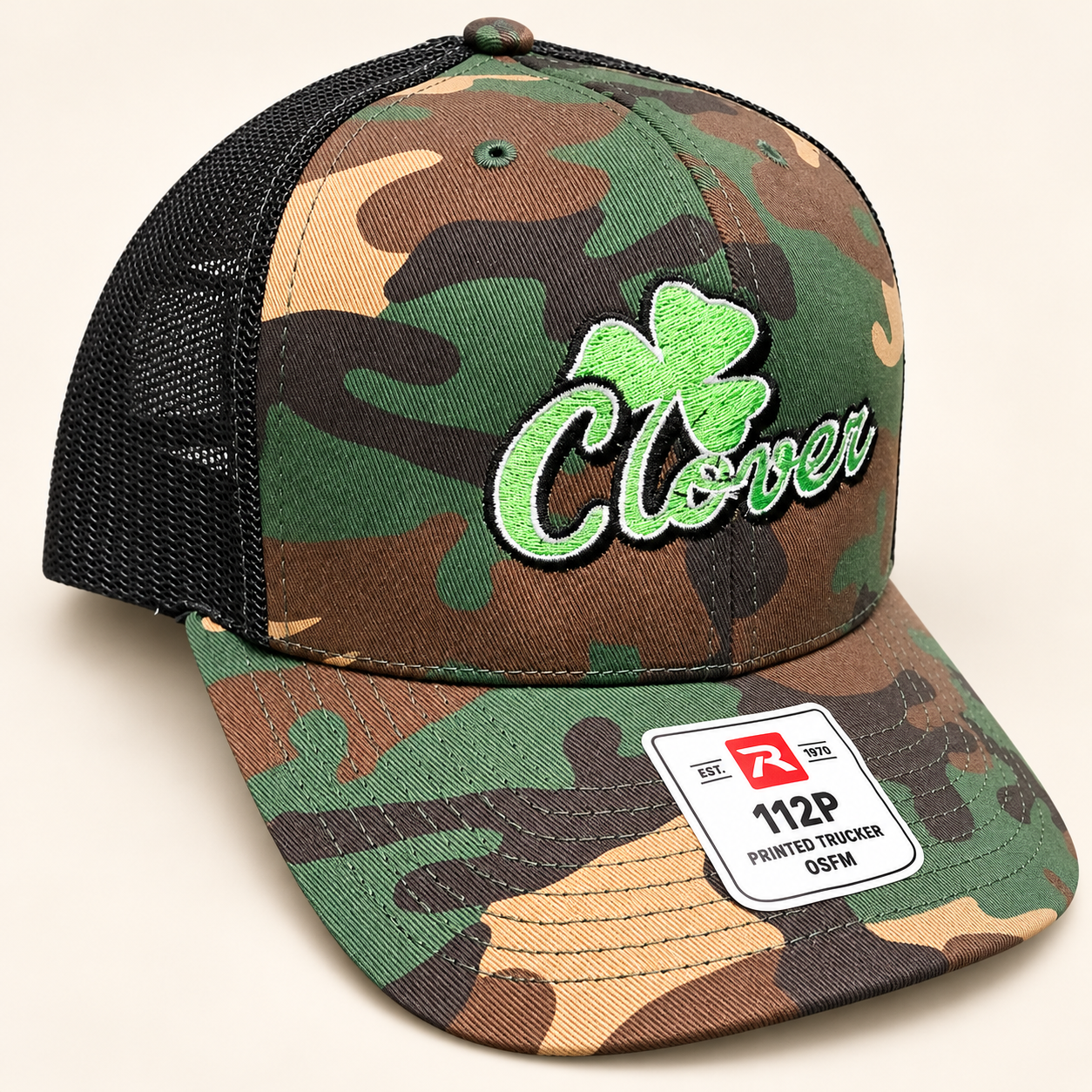 Richardson 112P camo trucker hat with black mesh, green Clover script and a large clover outlined in white and black
